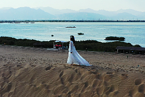 4K石嘴山市沙湖旅游景区湖面绿地白衣女性在沙漠里行走视频素材